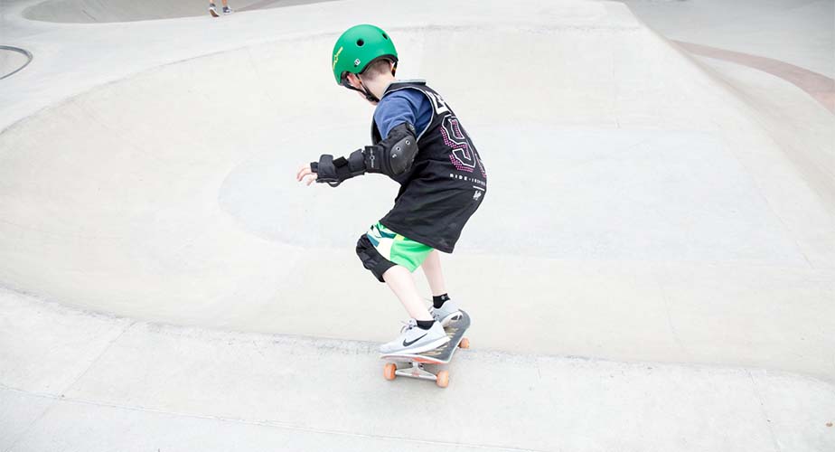 Chill youth rolling down a concrete ramp at a skatepark