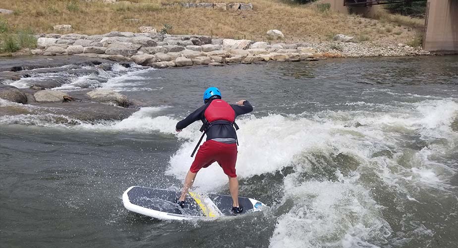 Chill youth riding a surfboard in the river