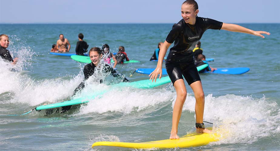 Chill youth standing smiling on a surfboard while riding a wave
