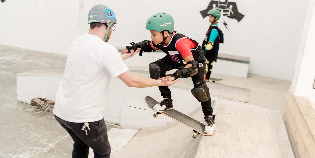 Chill mentor helping a youth drop in on a skateramp