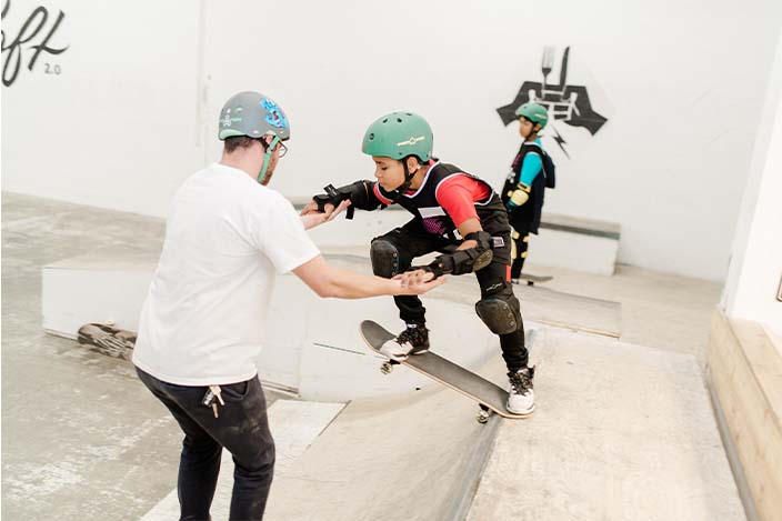 Chill Mentor helping a youth drop in on a skateboard ramp