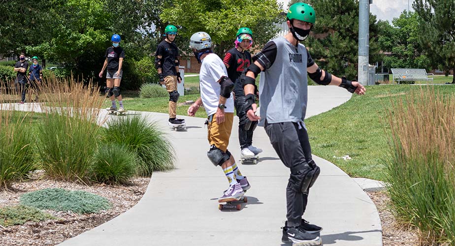 Chill youth skate down a path in a line together