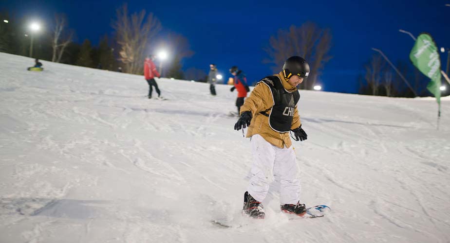 Chill youth snowboarding down a hill with a big grin