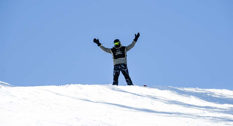 Chill youth waving his hands in the air from the top of a mountain