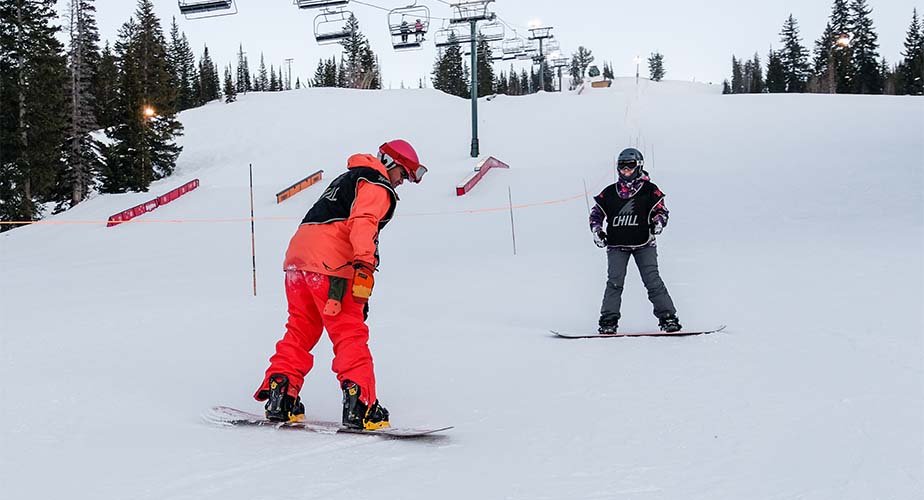 Chill mentor coaching as a youth learns to do a toeside turn dressed in bright orange