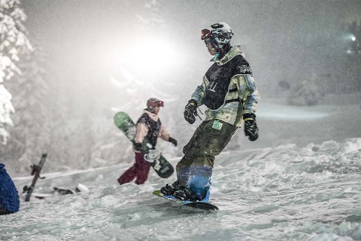 Chill youth snowboarding in the evening with snow falling around him