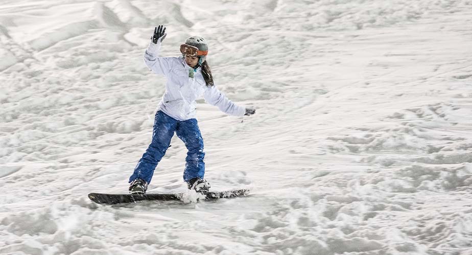 Chill youth snowboards down the slope with arms up