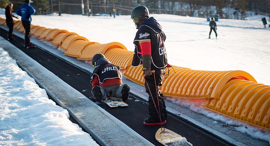 Chill snowboarders standing on a magic carpet lift