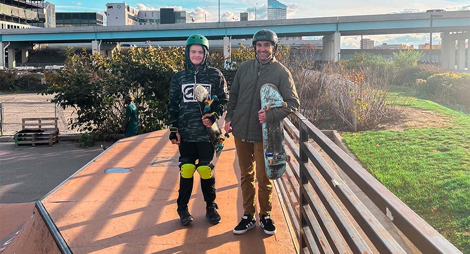 Chill youth and mentor standing smiling with skateboards