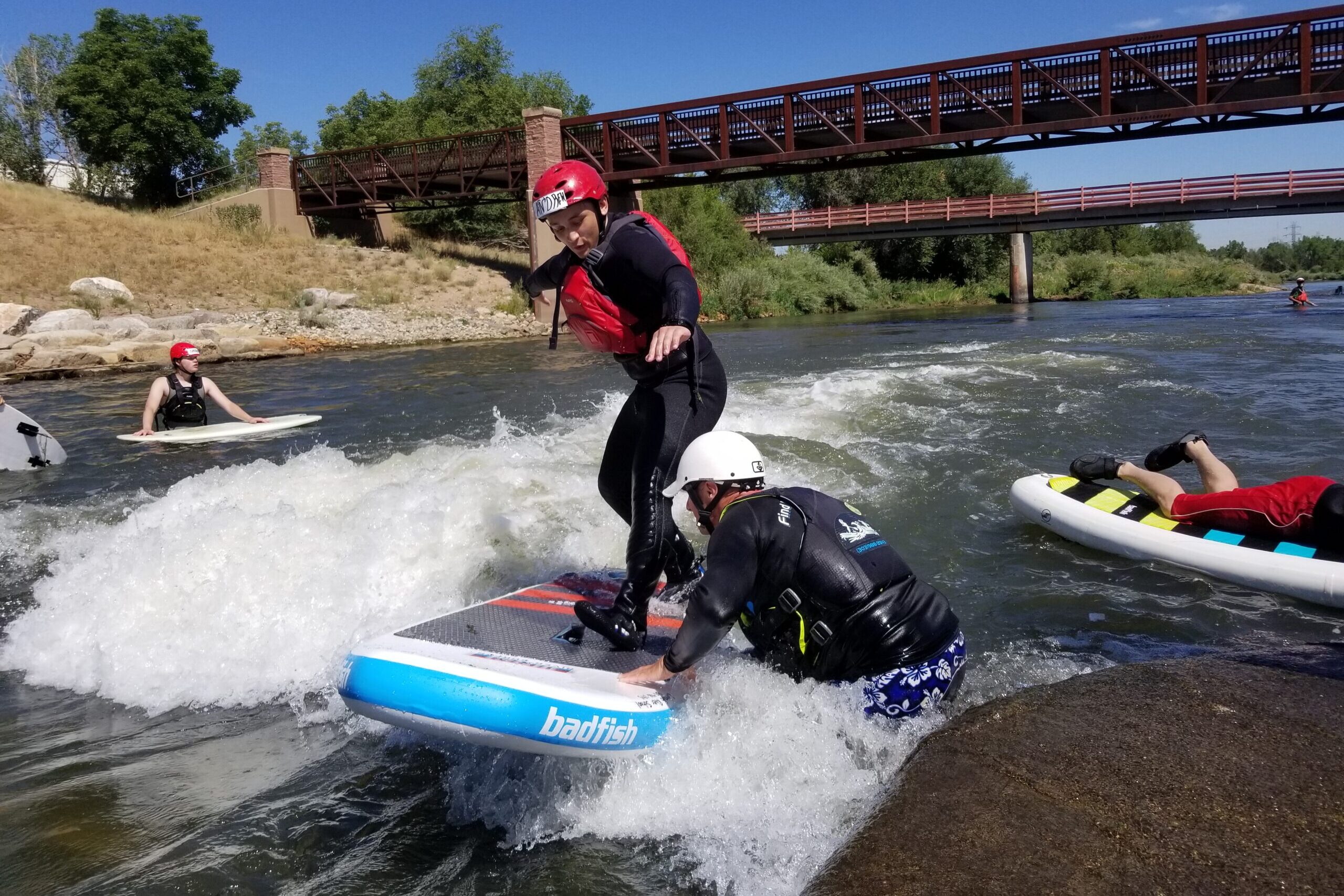 A Chill youth river surfing with an instructor helping.