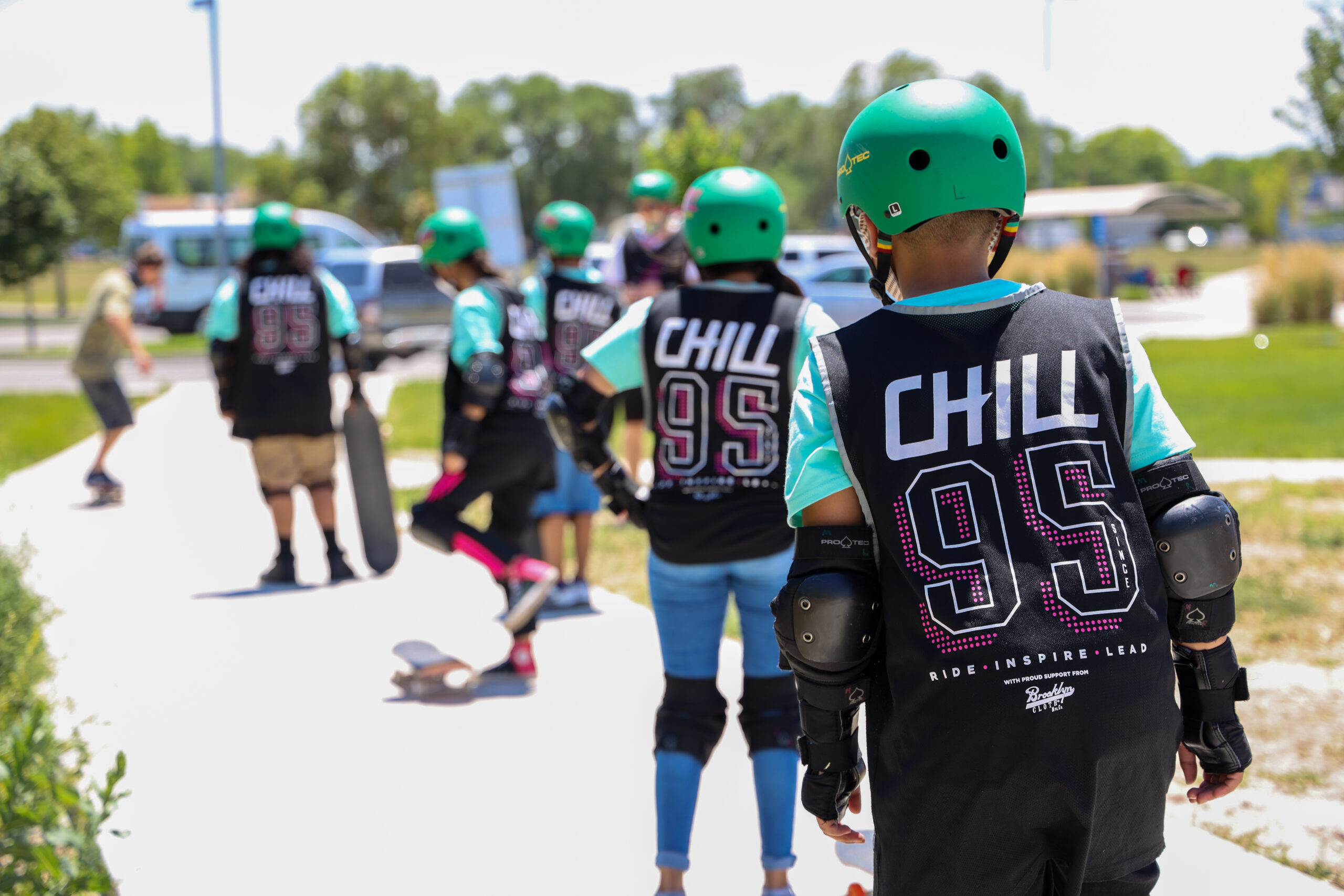 A group of Chill youth standing in a row on a path at the skatepark.