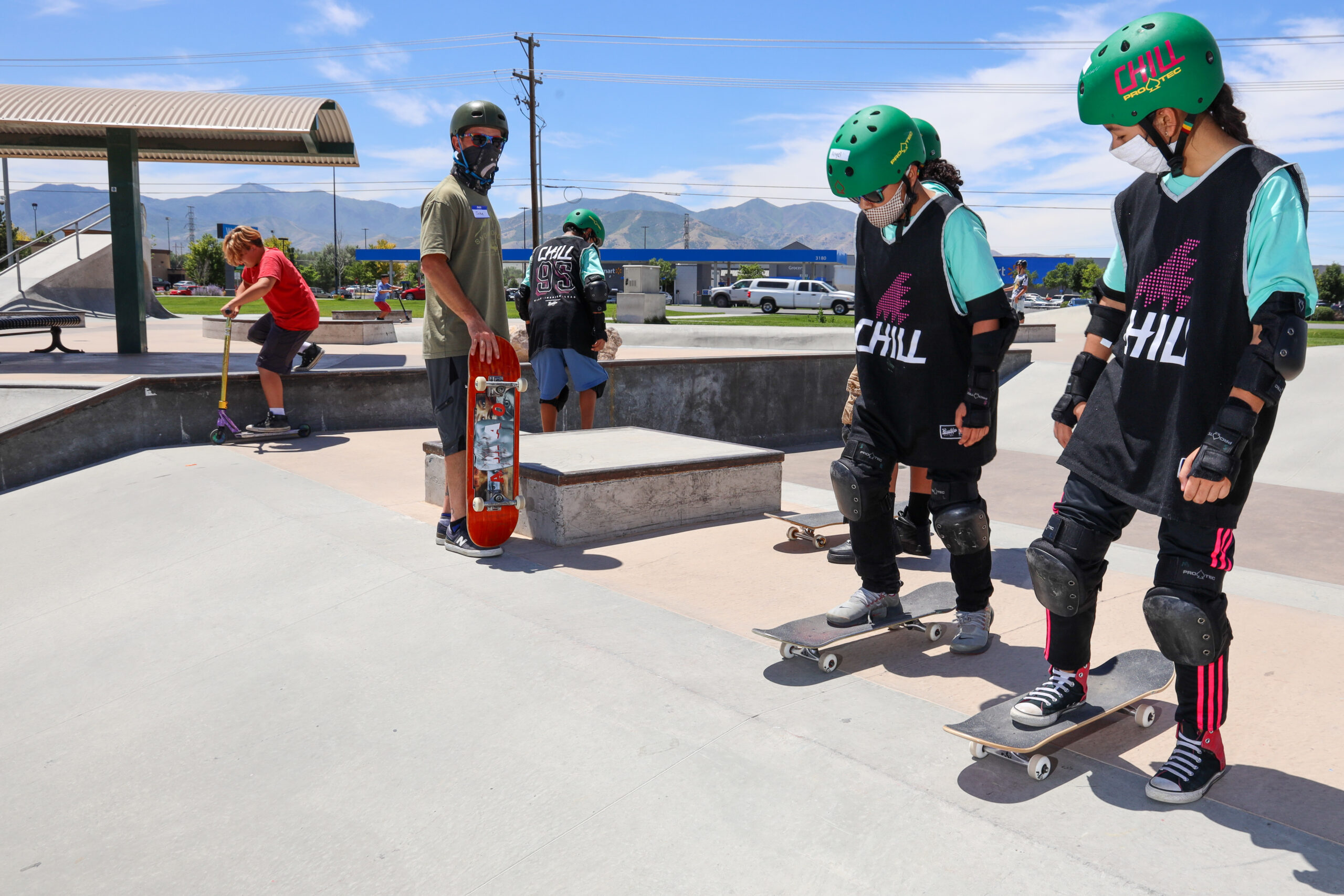 Two Chill youth about to skate down a ramp at the skatepark.