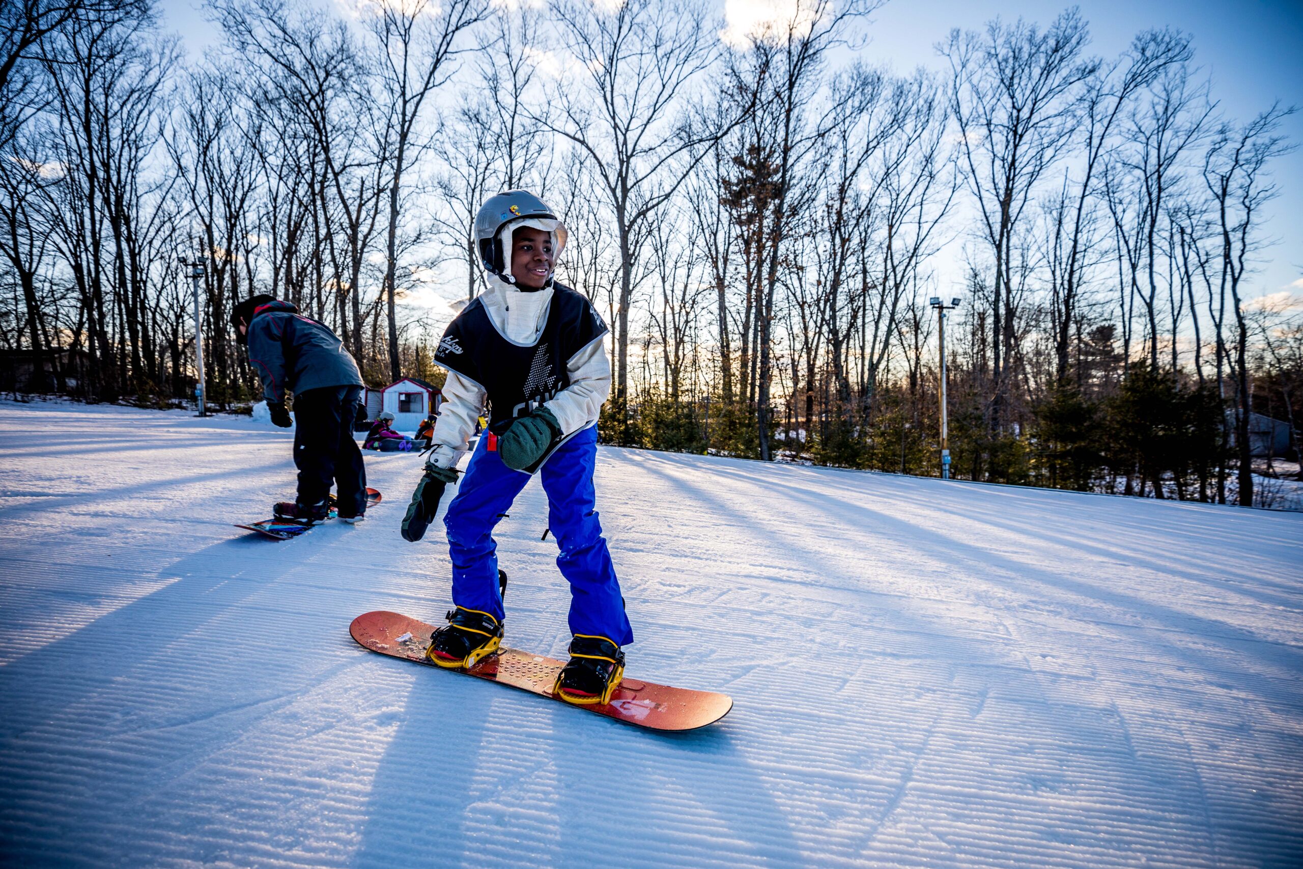 Chill youth snowboarding with light filtering through the trees in the background.