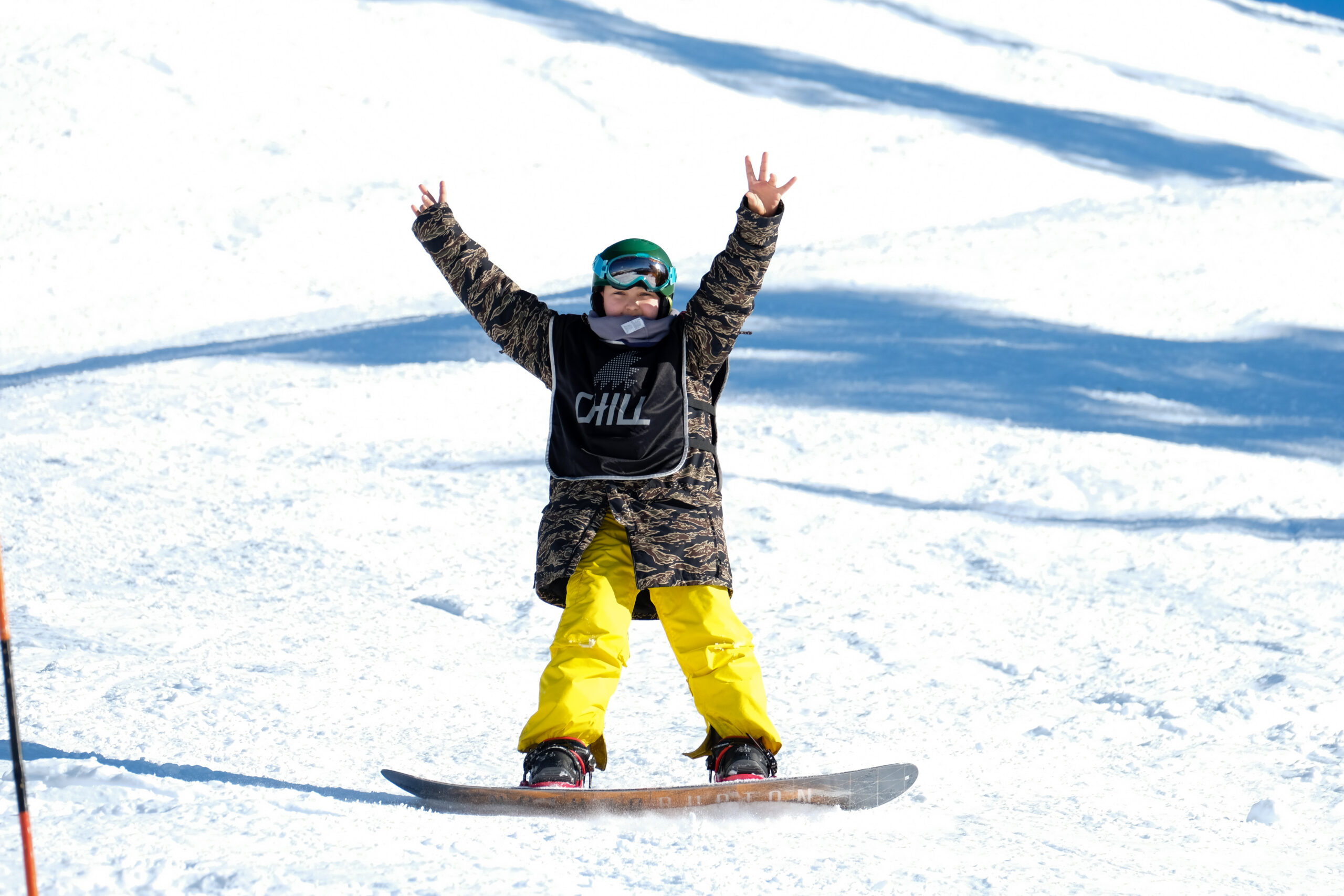 Chill youth snowboarding with their arms in the air in excitement.