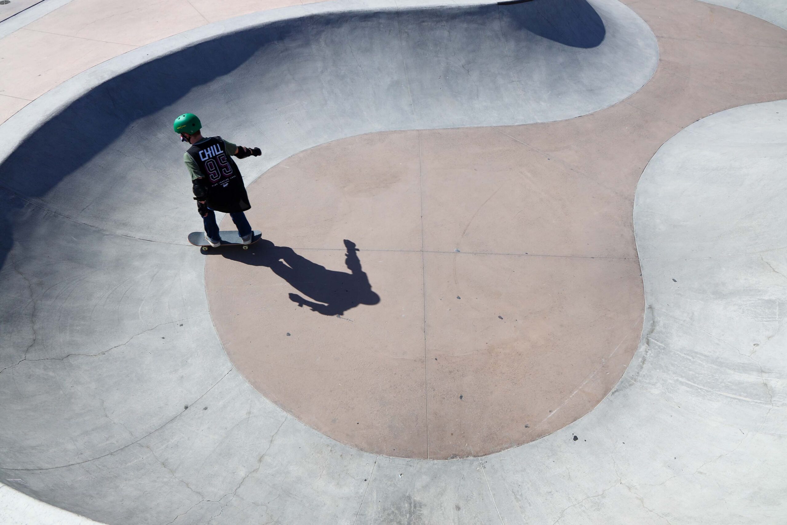 A Chill youth skating in a bowl at the skatepark.