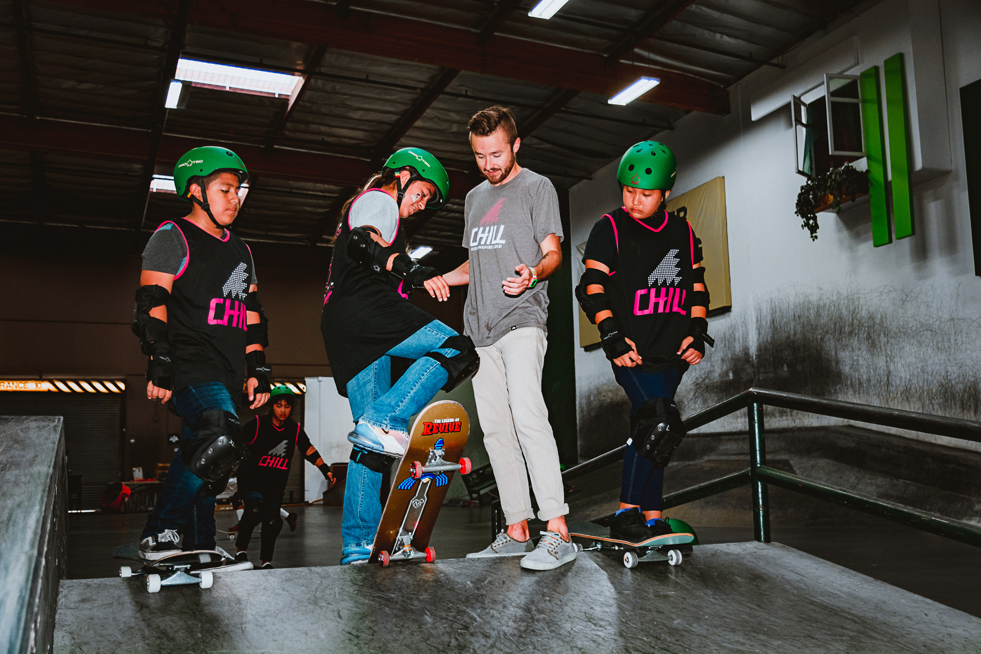 Chill Program Coordinator helps a youth drop into a ramp at the Berrics Skatepark.
