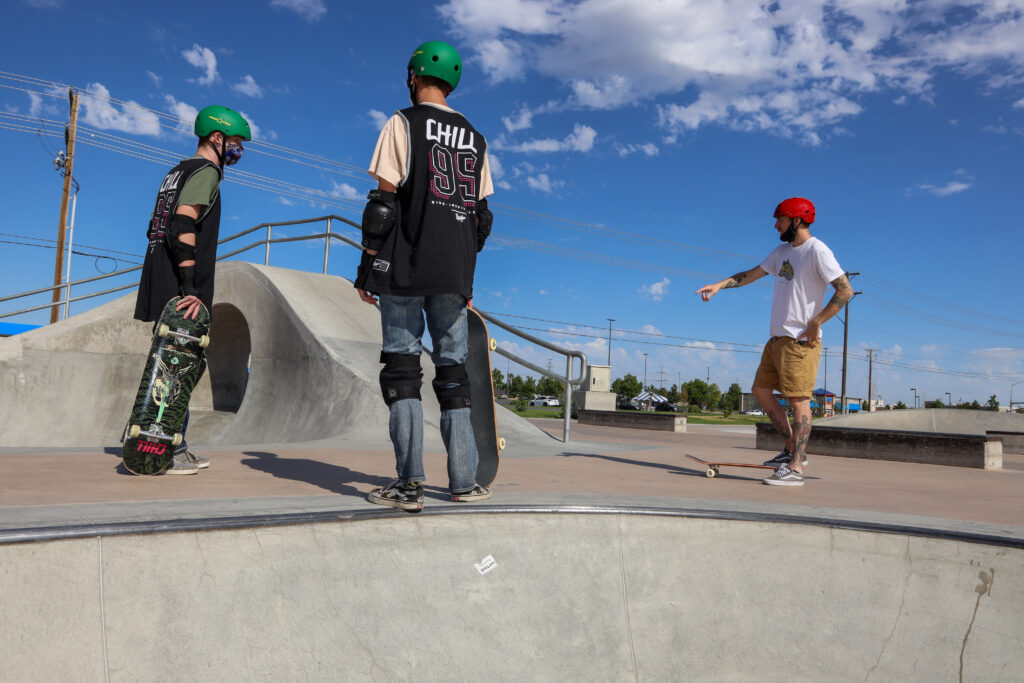 A Chill mentor coaching youth in the skatepark.