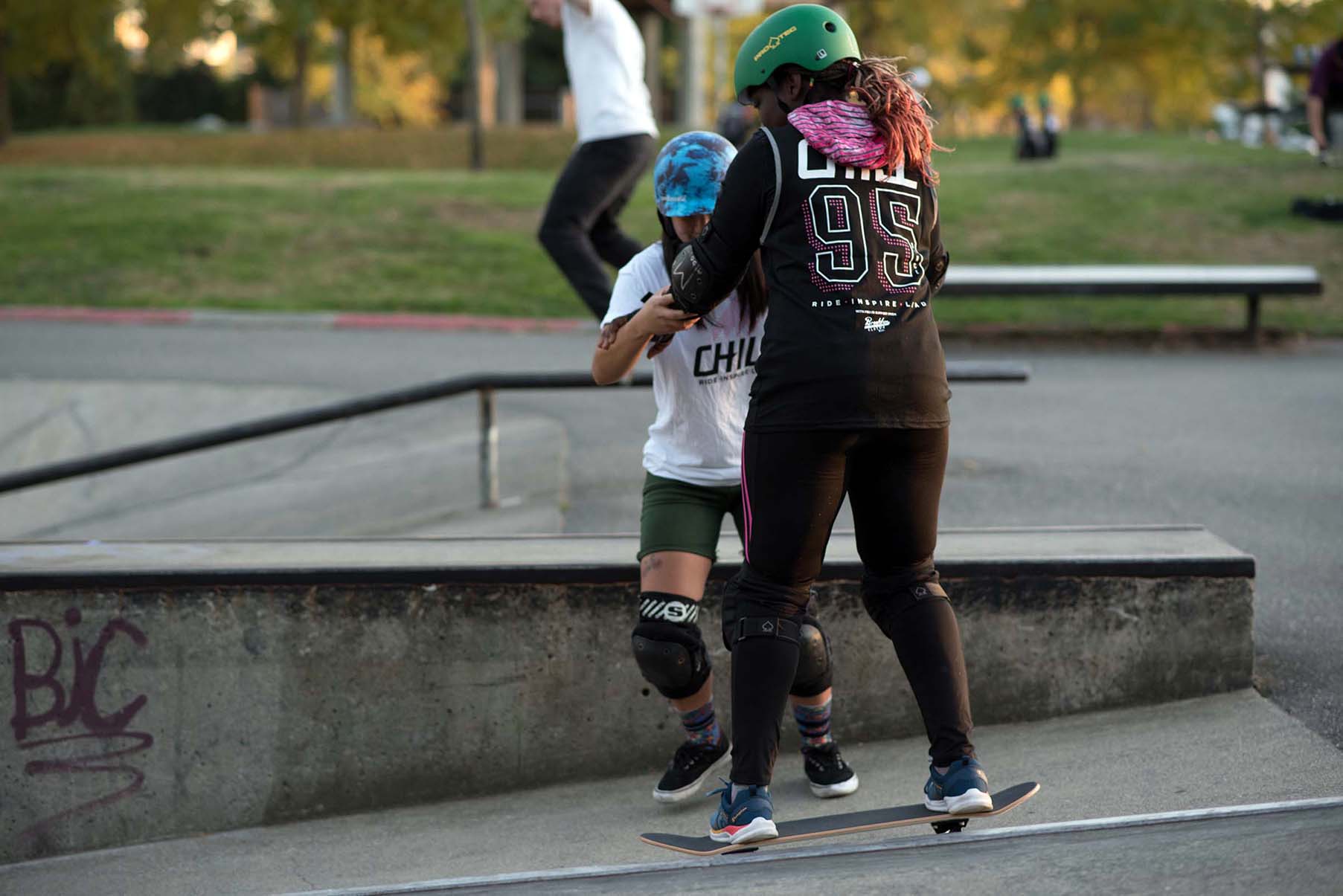 Chill mentor helping a youth on their skateboard.