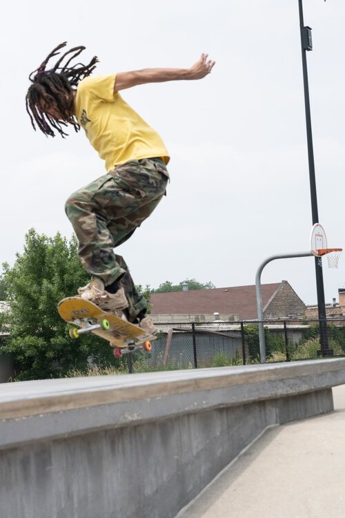 A youth skateboarding in a yellow shirt