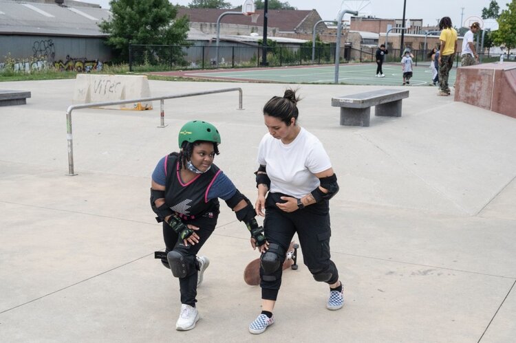 A youth works with an instructor skating.