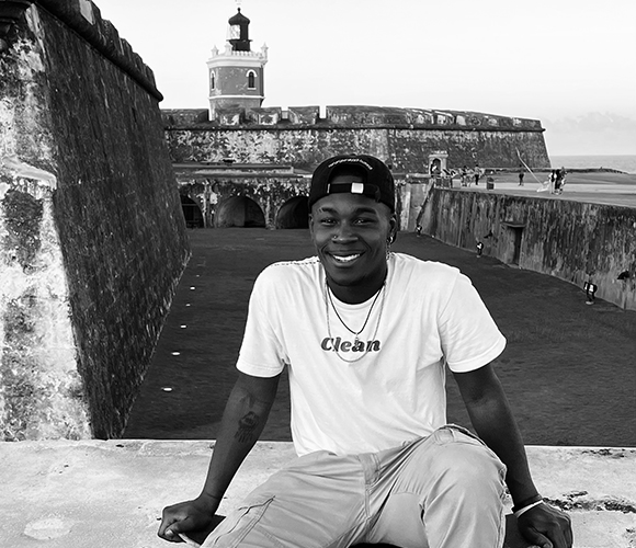 Man seated in front of a historical building.